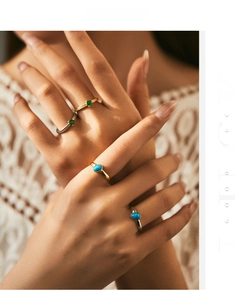 Detail shot of stacked minimalist rings with emerald and blue opal stones on hand