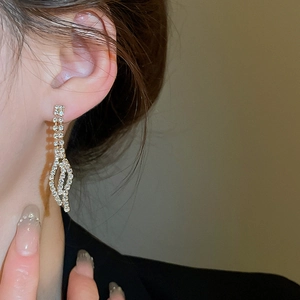 Close-up of gold leaf drop earrings with sparkling rhinestones worn by a model