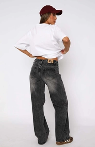 Detail view of high-waisted straight leg jeans with vintage wash and brand logo on leather patch