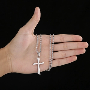 Silver polished stainless steel cross pendant necklace with a small diamond held in hand