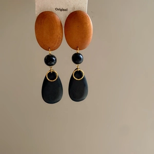 Detail of ethnic style fish earrings featuring wood texture and black teardrop pendant