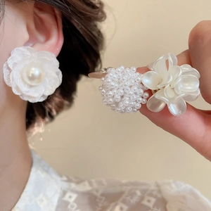 Dettaglio di orecchini a fiore in tessuto con perle e delicati petali in resina