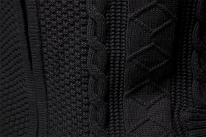 Macro di maglione nero in maglia spessa con trame a treccia e dettagli a nido d'ape