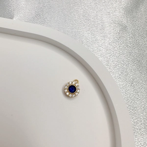 Close-up of a gold round pendant featuring a blue gem surrounded by white stones