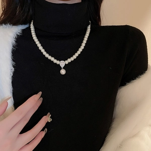 Close-up of pearl necklace with a teardrop zircon pendant on a black turtleneck sweater