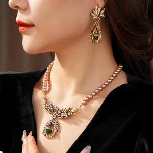 Detail of vintage necklace and earrings with pink pearls, gold leaf and green gemstones