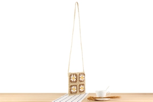 Détail du motif marguerite au crochet fait main sur un sac à bandoulière tissé élégant