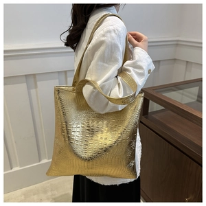 Close-up of golden crocodile pattern tote bag with metallic texture and long handles