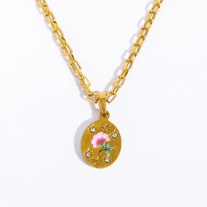 Detail of gold oval pendant featuring a pink painted flower and sparkling crystal accents