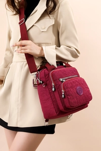 Détail du sac bandoulière en nylon bordeaux avec poches multiples et large sangle