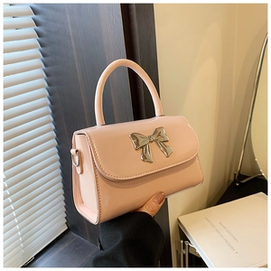 Dettaglio di una borsa in pelle verniciata rosa con un elegante fiocco metallico argento