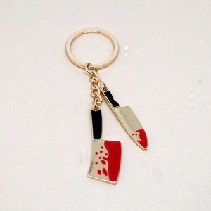 Halloween knife keychain with bloody gold cleaver and black machete charms on table