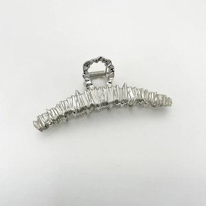 Detailed macro view of irregular pleated texture on large silver metallic hair claw clip