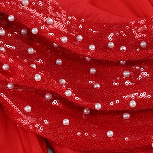 Vue macro du tissu de robe de soirée rouge avec paillettes, perles et maille fine