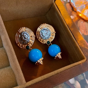 Close-up of vintage coin earrings with blue beads in a premium jewelry box