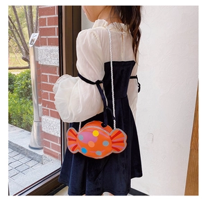 Petite fille portant un joli sac bandoulière orange en forme de bonbon à pois colorés