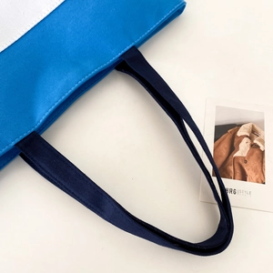 Detailed close-up of the blue and white canvas tote bag with durable navy blue handles