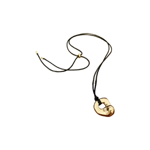 Irregular geometric gold pendant on a black adjustable cord necklace over a white background