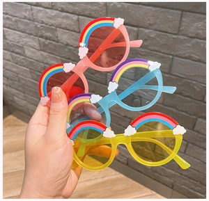 Close-up of children's round sunglasses with cute rainbow and cloud decor in pink, blue and yellow