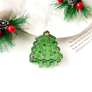 Detail of Christmas tree hair claw clip with glitter finish and colorful polka dot accents