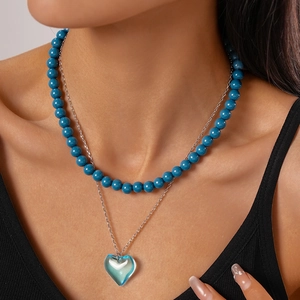Close-up of double-layered necklace with dark blue beads and clear blue heart pendant