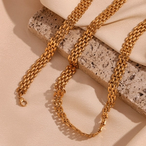Macro view of gold-plated mesh strap necklace on beige silk and stone background