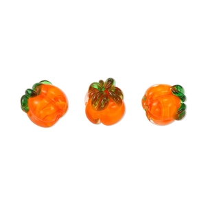 Close-up of orange glass pumpkin beads with green leaves for DIY jewelry making