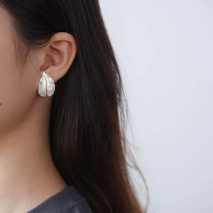 Detailed view of leaf-shaped silver earring with gold accents and a white pearl on ear