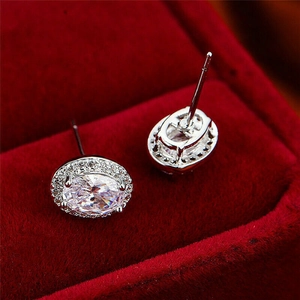 Elegant silver oval halo stud earrings with zircon stones on red velvet backdrop