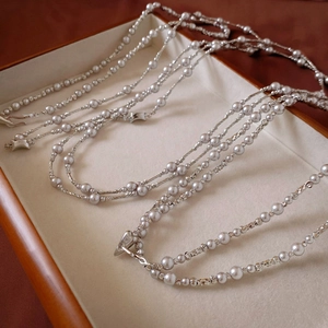 Detail of multi-layered silver pearl necklace with vintage metal clasp on wooden tray