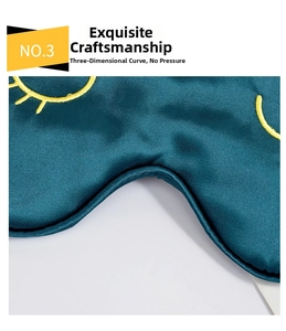Nahaufnahme einer dunkelgrünen Seiden-Schlafmaske mit gelber Wimpern-Bestickung, sehr weich.