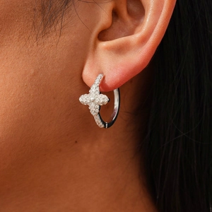 Detailed close-up of a silver flower earring with zircons worn on the earlobe