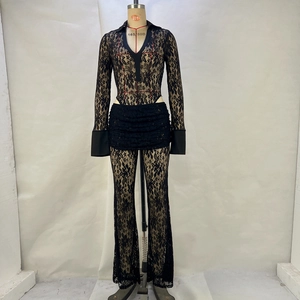 Detailed close-up of black lace jumpsuit with sheer long sleeves and tiered ruffle skirt detail