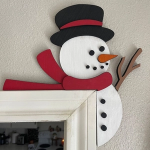 Détail de décoration d'angle de porte bonhomme de neige en bois avec écharpe rouge