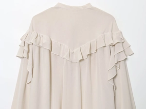 Detailed view of beige ruffled layers on the back of a women's long sleeve blouse