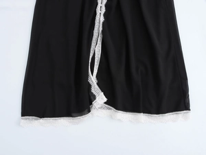 Detail of elegant black dress showing white lace hem and small button split design