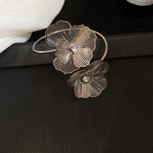 Detailed view of silver open cuff bracelet with hollow floral design and sparkling zircons