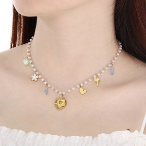 Gold heart and sun pendants on a pearl beaded necklace worn by a model