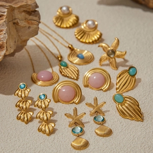 Golden sea-themed jewelry set with starfish, shells and pearls on sandy background