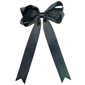 Macro detail of the smooth black satin texture and fine ribbed weave of the bow hair clip
