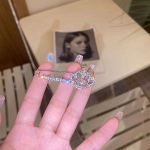 Close-up of sparkling silver bow crown brooch with rhinestones held in hand