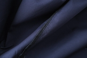 Macro view of stitching and fine cotton poplin texture on a navy blue shirt