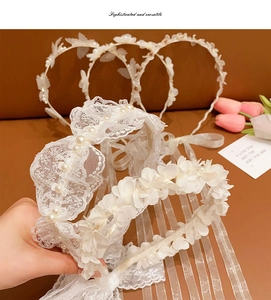 Detailed view of white lace headband with 3D flowers, pearls, and long tulle ribbons