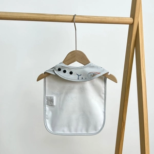 Detail of waterproof baby bib with nautical whale prints and adjustable snap closures