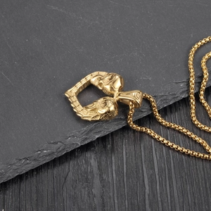 Gros plan du pendentif cœur double crâne doré avec sa chaîne à billes assortie