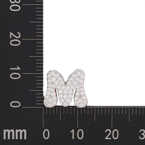 Macro shot of silver letter M charm with zircons measuring 12mm by 13mm on scale