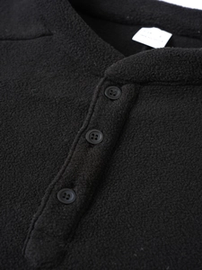 Close-up of black fleece sweatshirt featuring three-button placket and textured fabric
