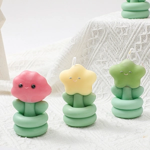 Trois bougies parfumées en forme de fleur avec visages souriants sur tricot