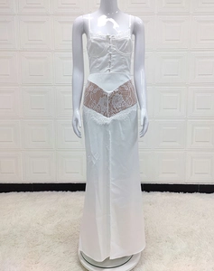 Detail of white maxi dress showing delicate lace patchwork and waist cut-out textures