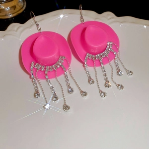Detailed close-up of pink cowboy hat earrings with sparkling rhinestone tassels